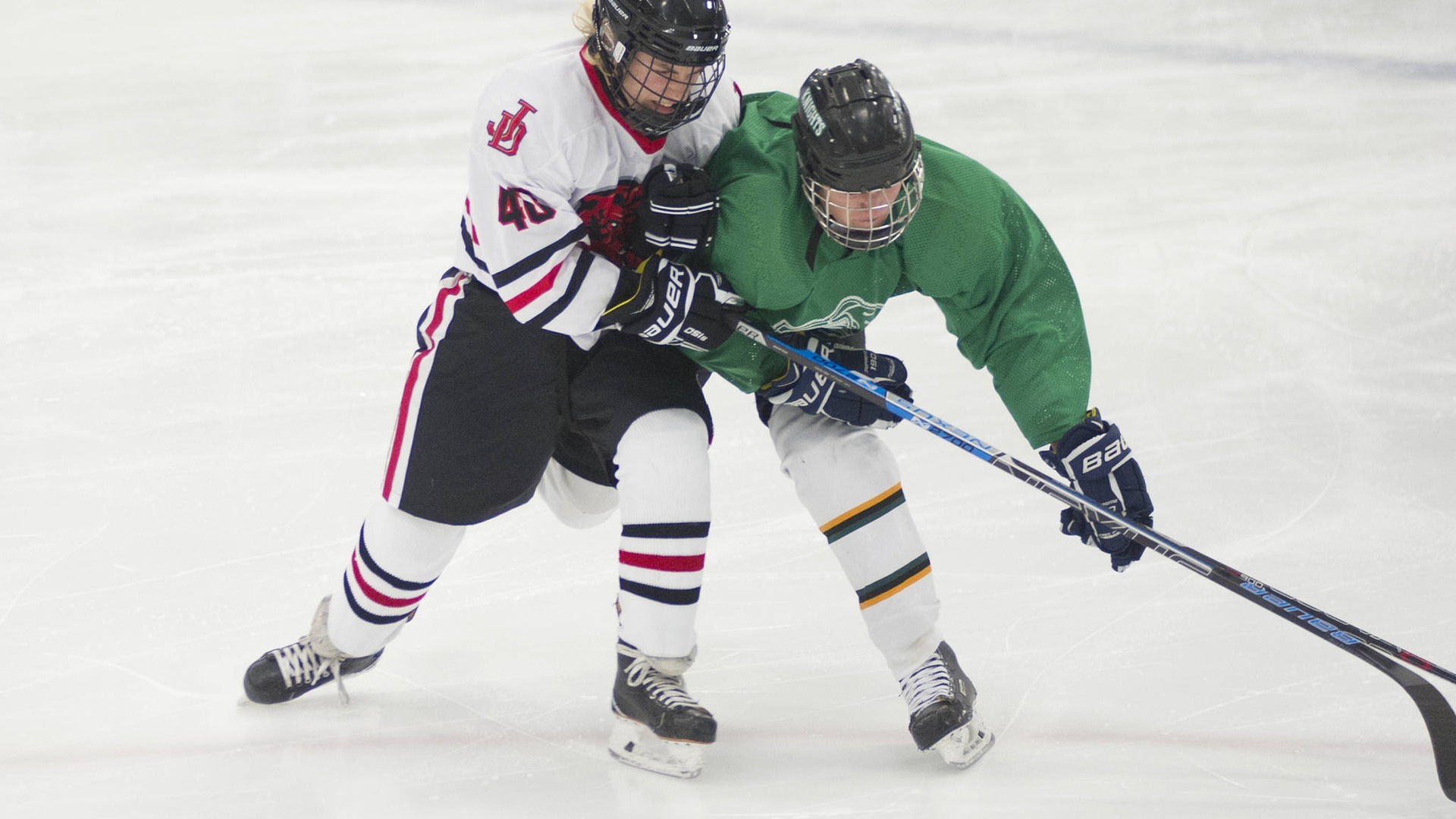 Ishockeyspelare i närkamp om pucken på isen under en hockeymatch