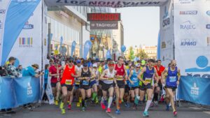 Löpare med startnummer under ett maratonlopp som passerar under portalen och den officiella matchklockan